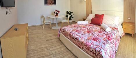 A modern bedroom with a large bed, bedside tables, a desk, and a chair.