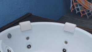 Ein weißes Whirlbad mit vier Düsen, auf einer Holzdielen-Terrasse platziert.