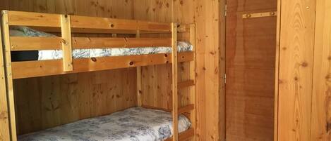 A bunk bed room with wooden walls and a door.