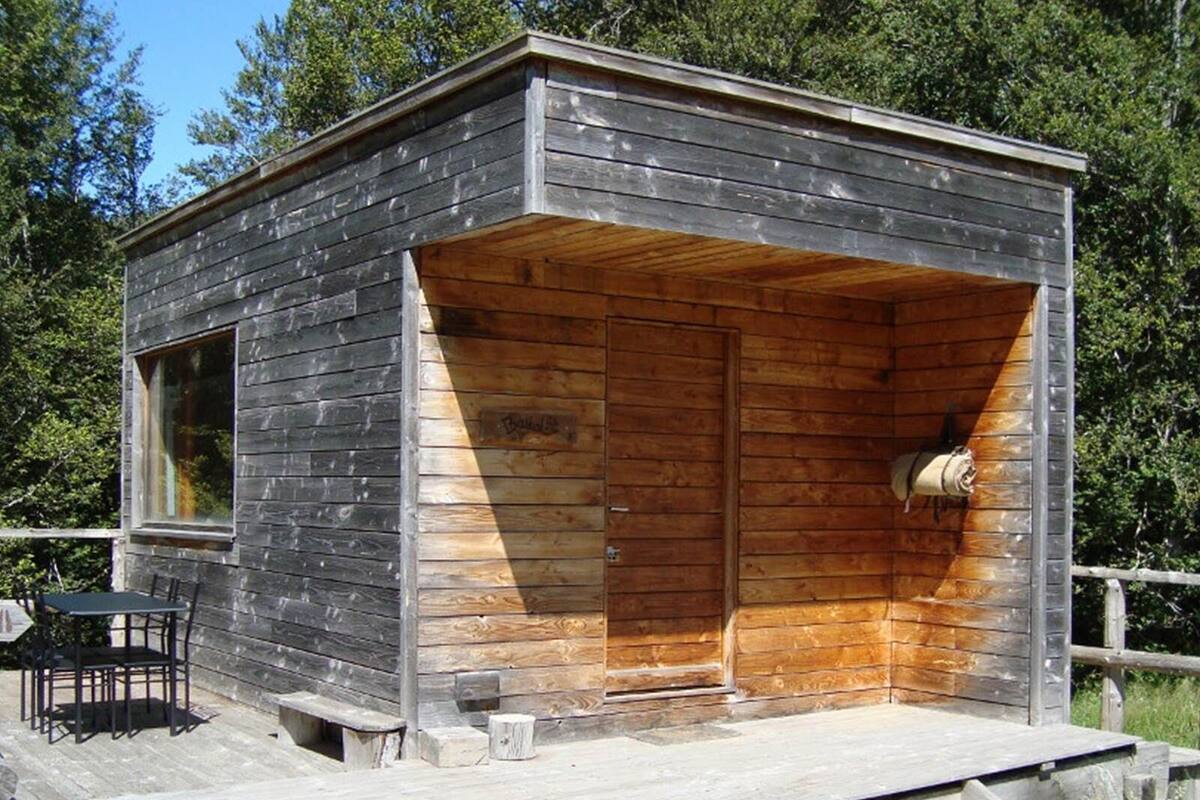 A small cabin with a wooden exterior, a single door, and a window.