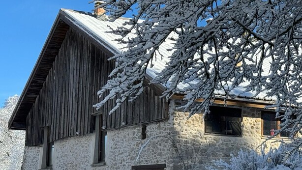 A stone building with a wooden facade, multiple windows, and snow-covered surroundings. - Vercors Intense (Vassieux-en-Vercors)