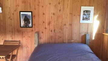 A wooden-paneled room with a bed, a framed photo on the wall, and a small table.