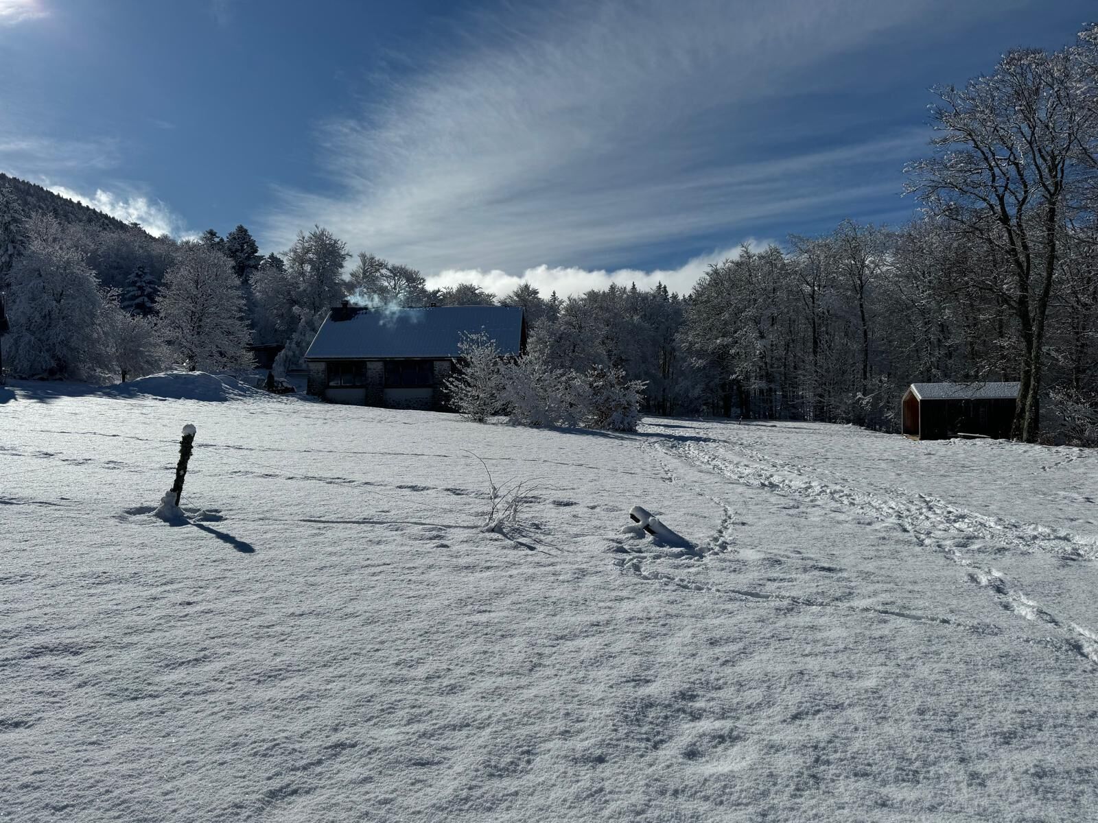 Lumipeitteinen maisema, jossa on talo ja varasto.