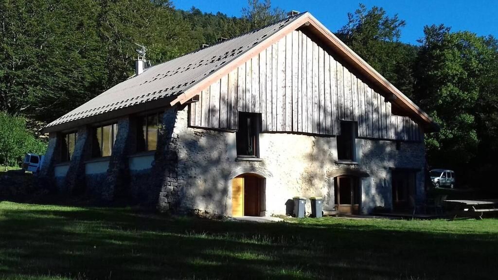 A rustic wooden house with a sloped roof, a front porch, and a small attached garage.