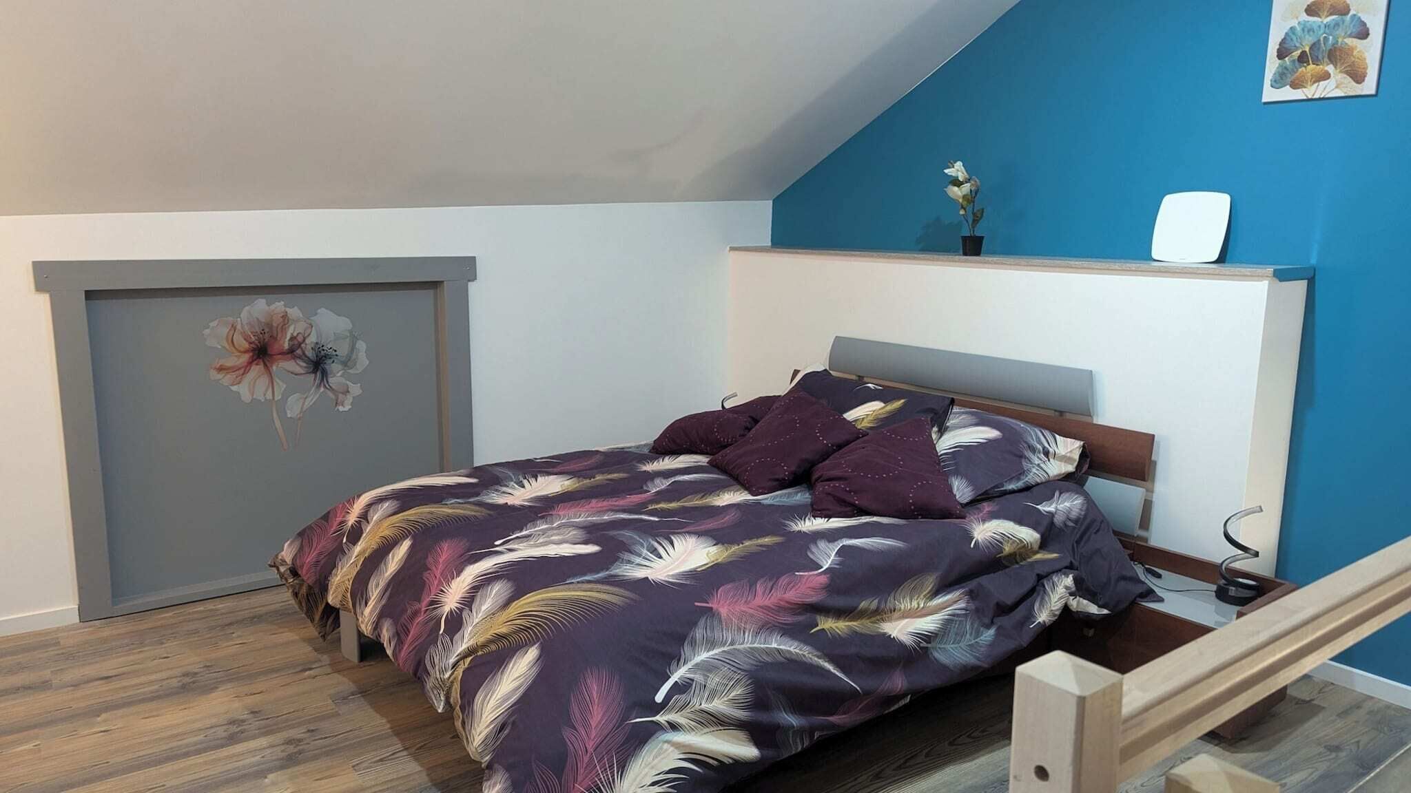A bedroom with a bed, a desk, a chair, and a blue wall.
