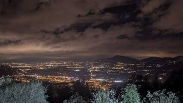 A nighttime cityscape with a view of a city spread across a valley, surrounded by hills.