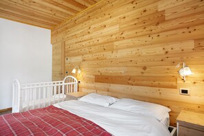 Une chambre à coucher aux murs lambrissés, avec un lit, des tables de chevet et des lampes fixées au mur.