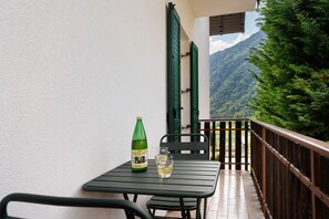 Un balcon avec une table, une bouteille et un verre.
