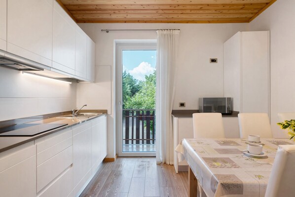 Une cuisine compacte avec des meubles blancs, un four à micro-ondes et un coin repas avec une table dressée pour deux personnes.