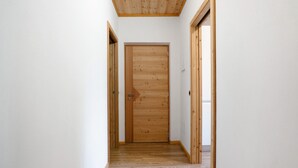 A narrow hallway with wooden flooring and doors, leading to a room with a wooden door. - Apartment 'Agritur Montibeller Fravort' with Mountain View, Shared Garden and Wi-Fi (Roncegno Terme)