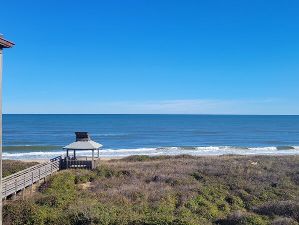 A beach view with a wooden structure, possibly a gazebo, overlooking the ocean. - Duck Tales - Oceanfront : Steps from the beach : Newly renovated! (Kitty Hawk)
