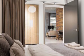 Un hotel moderno con una cama grande, un separador de madera y vista al comedor.