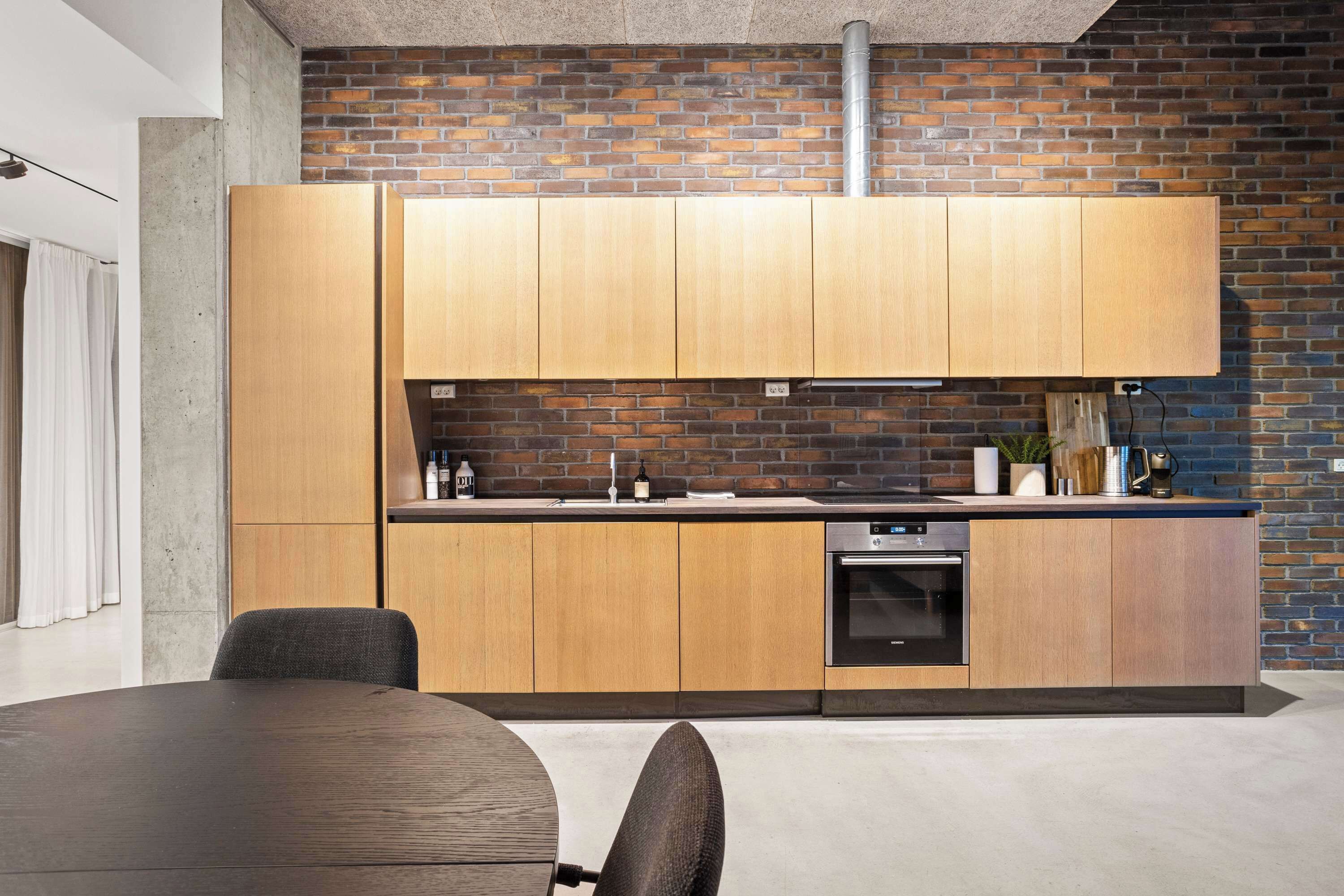 Una cocina moderna con armarios de madera, salpicadero de ladrillo y electrodomésticos de acero inoxidable.