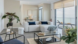 A modern living room with a sofa, coffee table, and a balcony with a view. - Villa Serenity - Pool & Sea View (Prazeres)