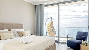 A modern hotel room with a large bed, a hanging chair, and a view of the sea. - Villa Serenity - Pool & Sea View (Prazeres)