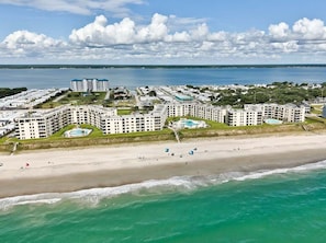 Ein Hotel an der Küste mit mehreren Gebäuden, einem Strand und einer weiten Wasserfläche.
