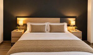 Un lit bien fait, recouvert d’une couverture à motifs, avec deux lampes de chevet et un mur sombre en arrière-plan.