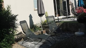 Een terras met lounge stoelen, een tafel en een kleine tafel met een bloempot.