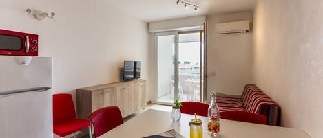 Un espacio habitable compacto con kitchenette, zona de comedor y rincón de estar con vistas.