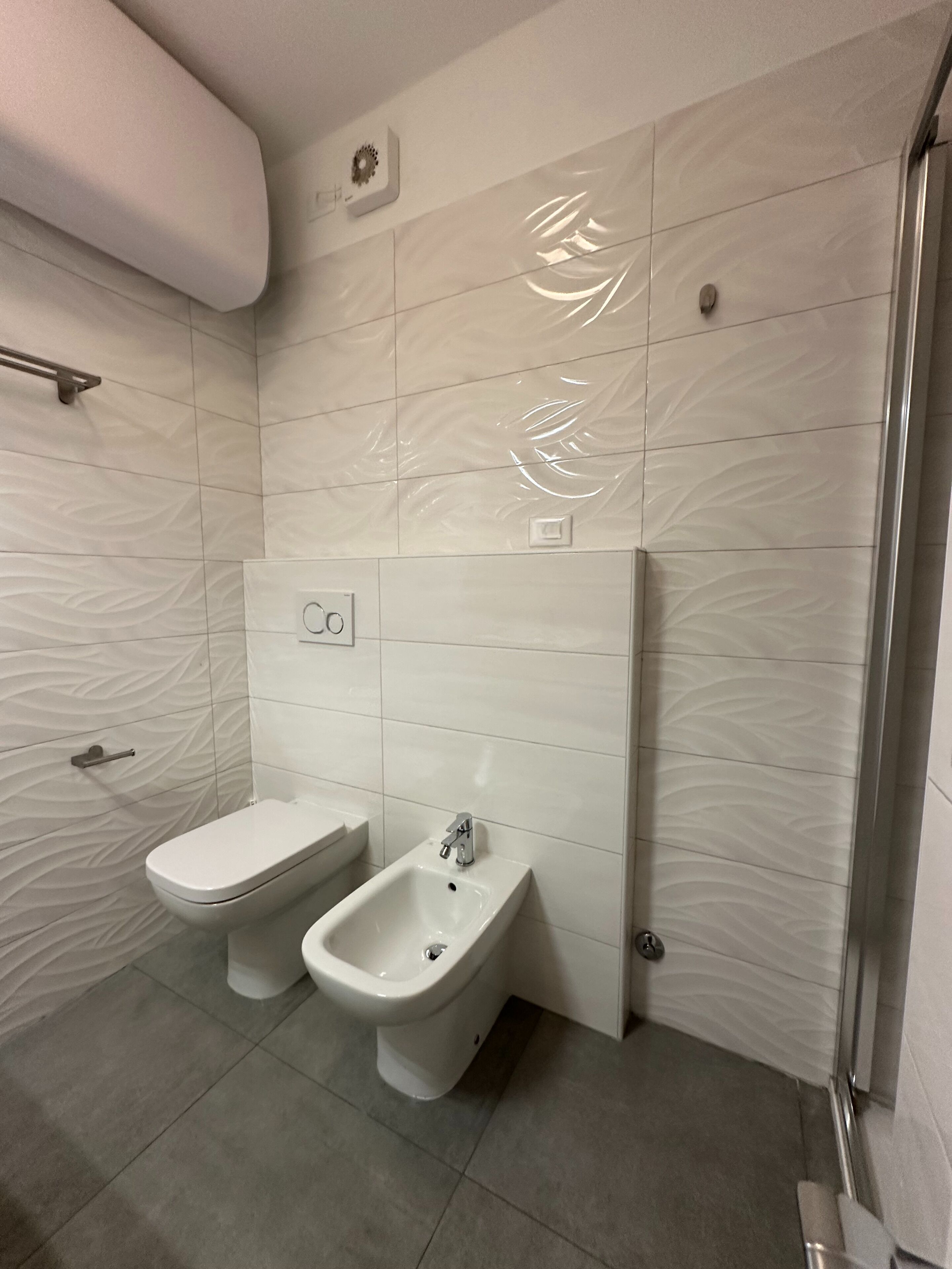 A modern bathroom with a toilet, bidet, and a shower area.