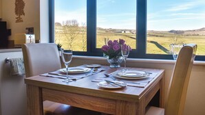 A dining table set with plates, cutlery, and a vase of purple flowers. - The Wolfs Den - UK49083 (Laneshawbridge, near Colne)