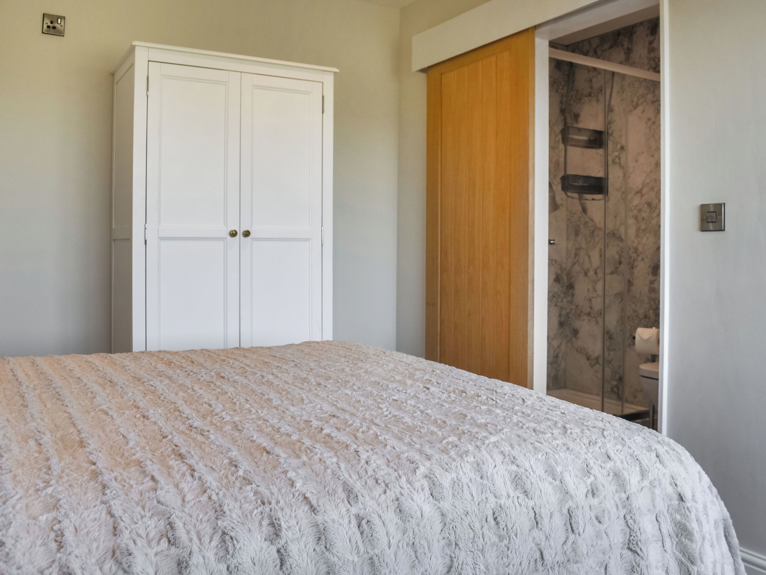 Ein Schlafzimmer mit Bett, Kleiderschrank und einem Badezimmer mit Dusche.