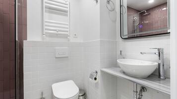 A modern bathroom with a white toilet, a sink, and a mirror.