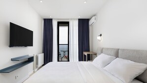 Een moderne hotelkamer met een groot bed, een flatscreen televisie aan de muur, een klein tafeltje en uitzicht op het omliggende landschap via een deur.