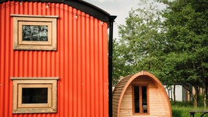A red building with two windows and a wooden structure with an arched entrance.