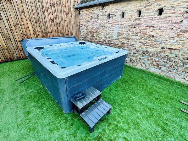 A hot tub with a wooden exterior and a stone wall backdrop. - Domaine des Retrouvailles - 20 people (Sainte-Anne-sur-Vilaine)