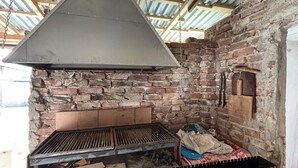 Una cocina al aire libre de ladrillo con una chimenea grande, una parrilla y un horno de ladrillo.