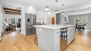 A modern kitchen with a large island, stainless steel appliances, and pendant lighting. - "Big Sky" Retreat Atop Sunapee / Ski + Lake Life (Newbury)