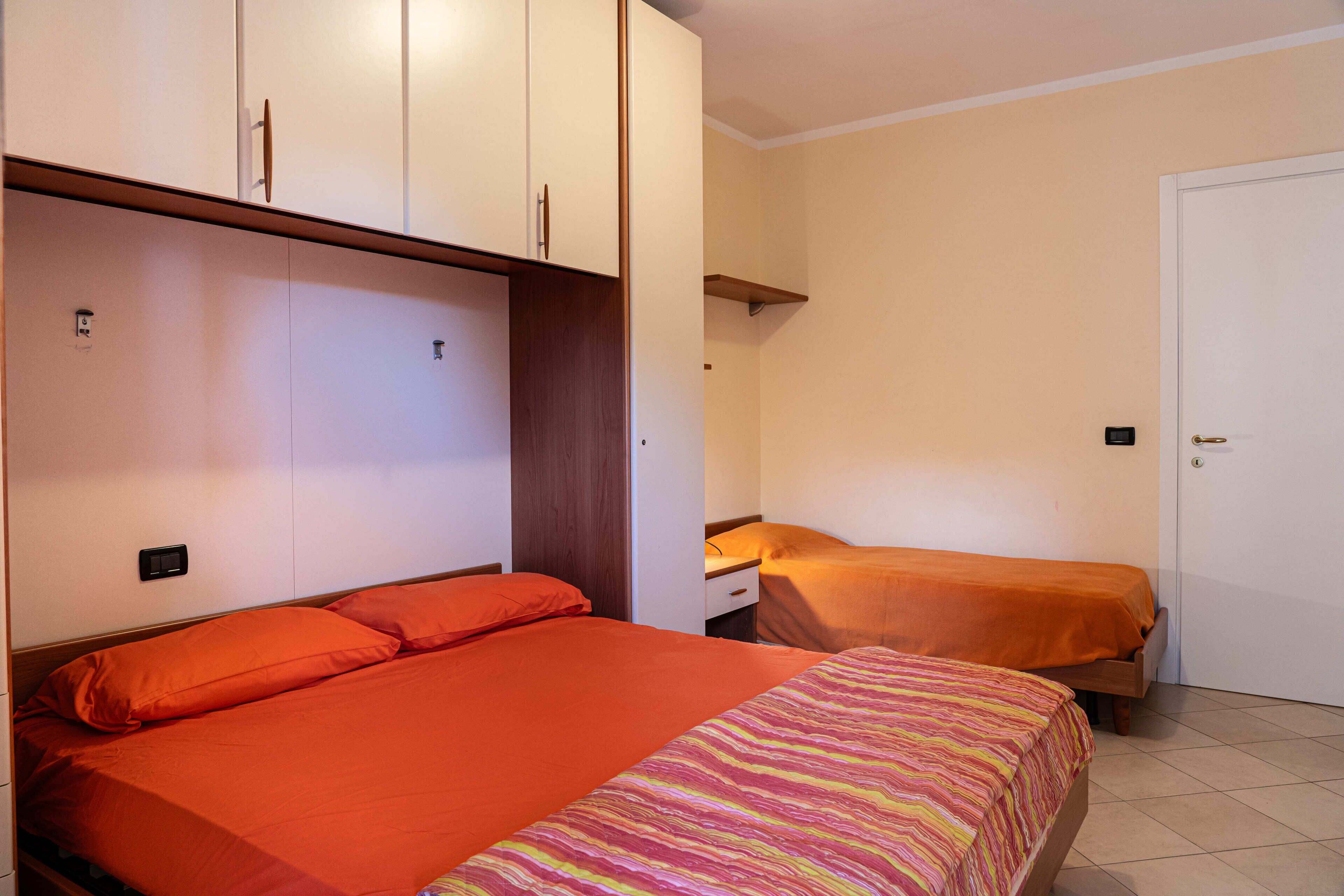 Une chambre avec deux lits, une armoire et une porte.