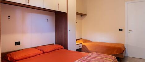 Un dormitorio con dos camas, un armario y una puerta.