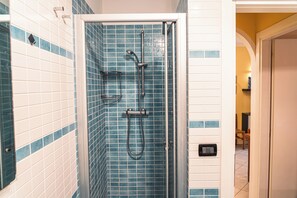Ducha con puerta de vidrio, azulejos azules y blancos, y panel de control.
