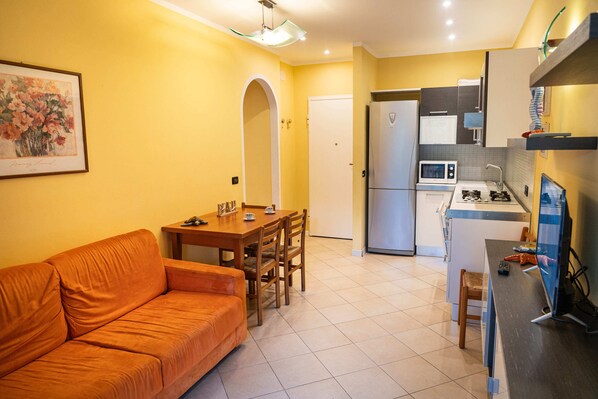 Un espacio habitable compacto con sofá, mesa de comedor y kitchenette.