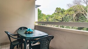 A balcony with a table and chairs, overlooking a view of trees. - Comfortable Stay Near the Beach in Bibione (San Michele al Tagliamento)