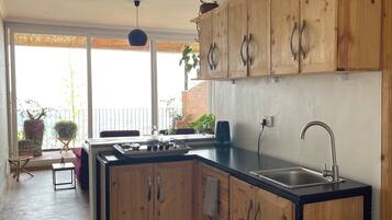 A modern kitchen with wooden cabinets, a black countertop, and a stainless steel sink.
