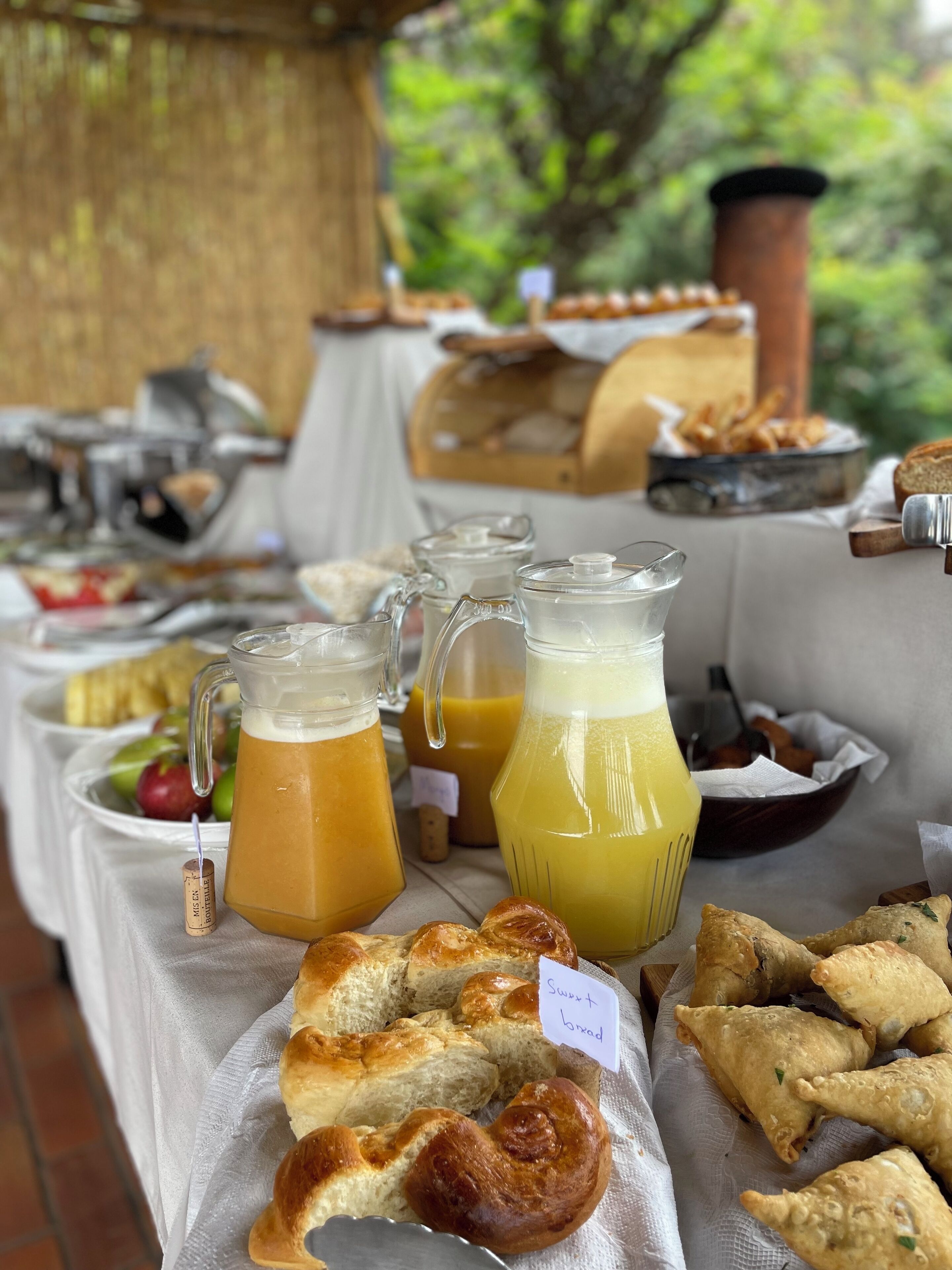 Ein Frühstücksbuffet mit verschiedenen Speisen, darunter Backwaren und ein Krug Orangensaft.