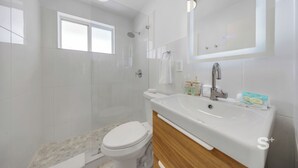 Ein modernes Badezimmer mit Toilette, Waschbecken und Dusche.
