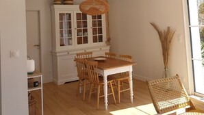 A spacious room with a wooden dining table, white cabinets, wicker chairs, and a large wall clock.