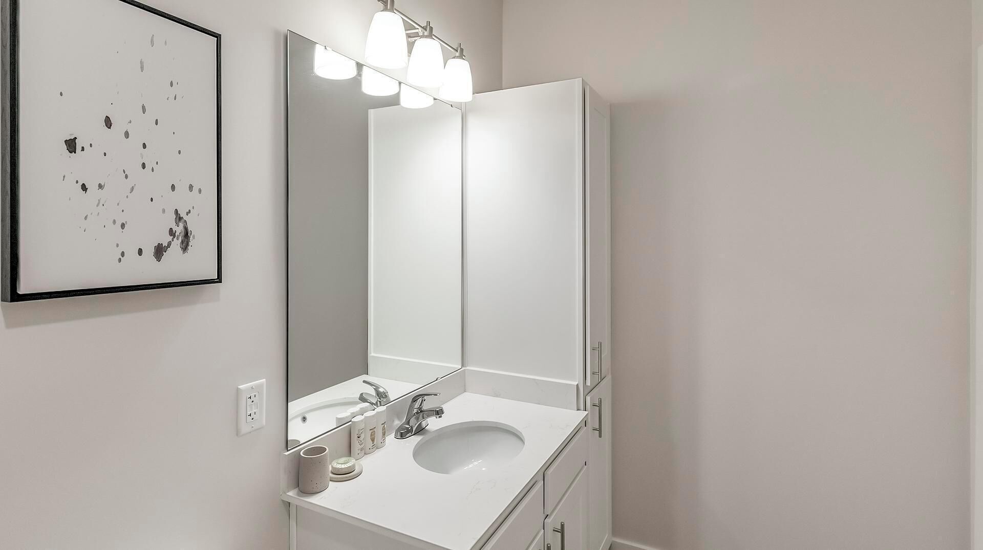 Un bany modern amb un mirall gran, un lavabo blanc i una làmpada penjant a sobre.
