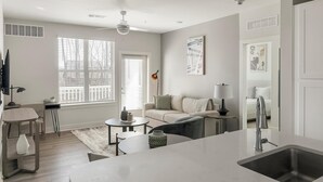 A modern kitchen with a central island, a dining area with a table and chairs, and a living area with a sofa.