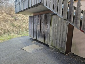 A wooden gate with numbered panels, a metal handrail, and a concrete step leading to a building.