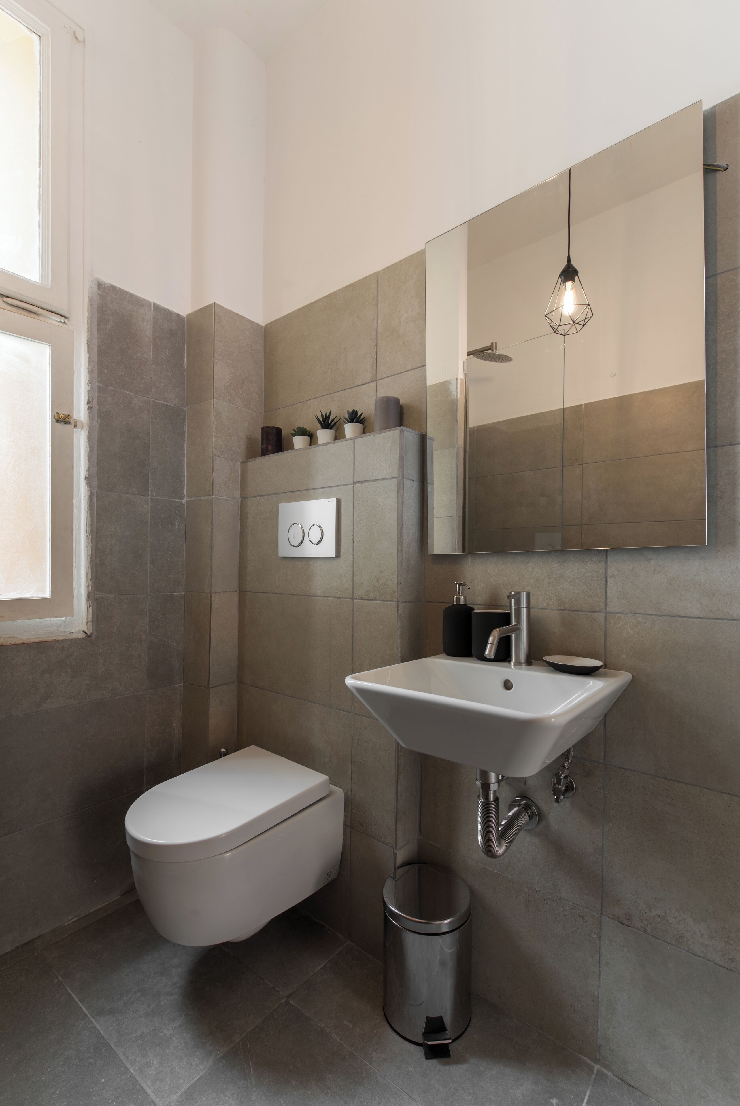 A modern bathroom with a toilet, sink, and mirror.