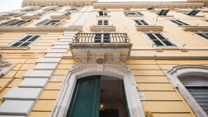 A building facade with multiple windows, a central entrance with a green door, and a balcony with a metal railing. - Apartment via Palestrina (Roma)