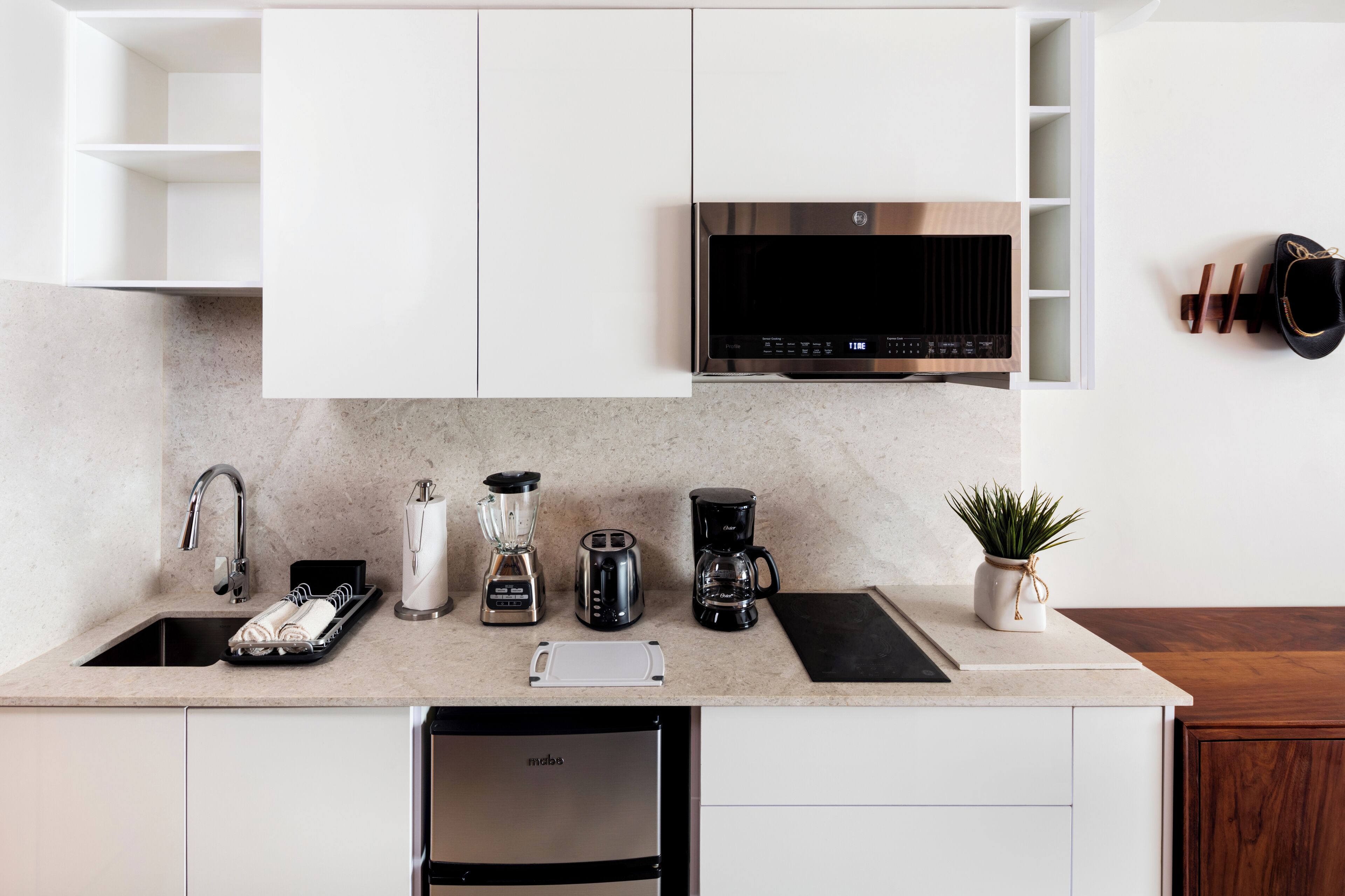 A modern kitchen with white cabinets, a stainless steel dishwasher, a coffee maker, a blender, and a toaster.