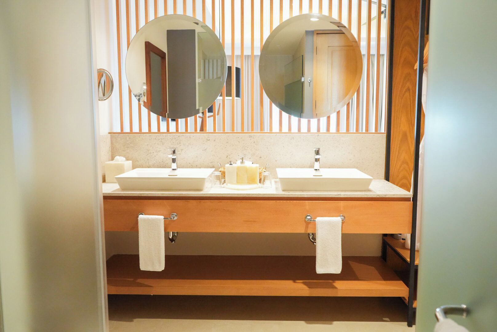 A bathroom with two sinks, a mirror, and striped wallpaper.