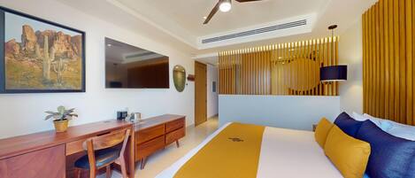 A modern hotel room with a bed, desk, chair, and a large painting on the wall.