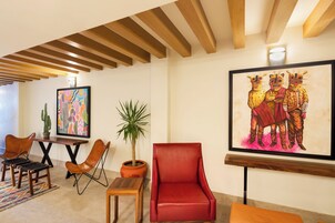 Un interior moderno con un sillón de cuero rojo, mesas de madera y una planta de cactus.